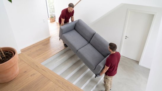 Zwei Männer tragen Sofa ins Haus